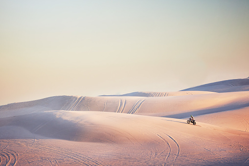 Sand landscape, motorbike or man on moto cross in desert space for sport workout, sunset ride or exercise on hill. Nature, sky or man riding for speed adventure in Dubai for training, fitness or race