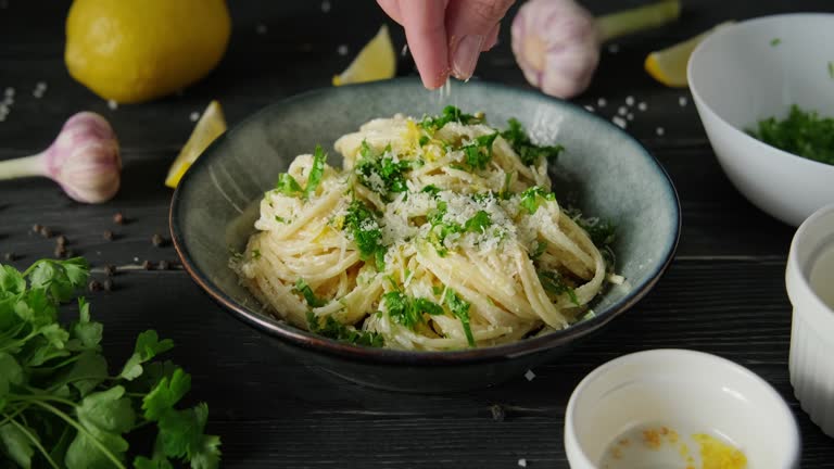 Sprinkling lemon pasta with parmesan cheese topping, person preparing spaghetti with white alfredo sauce, serving pasta for dinner, 4k footage