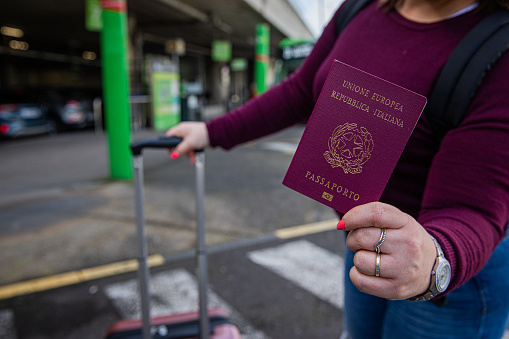 Primer plano de las manos de una turista italiana que sostiene su pasaporte en una estación de autobuses photo