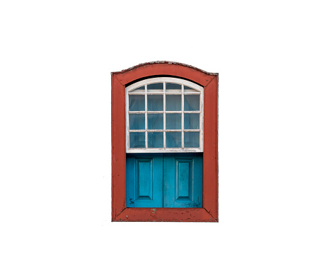 Old weathered window with curtains and green shutters on an old farmhouse.