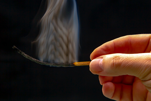 Extinct and fuming wooden match on a dark background close-up. smoke from a burning tree.