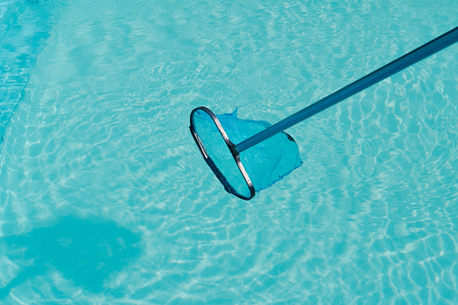 Ð¡leaning the water surface of an outdoor pool with a net