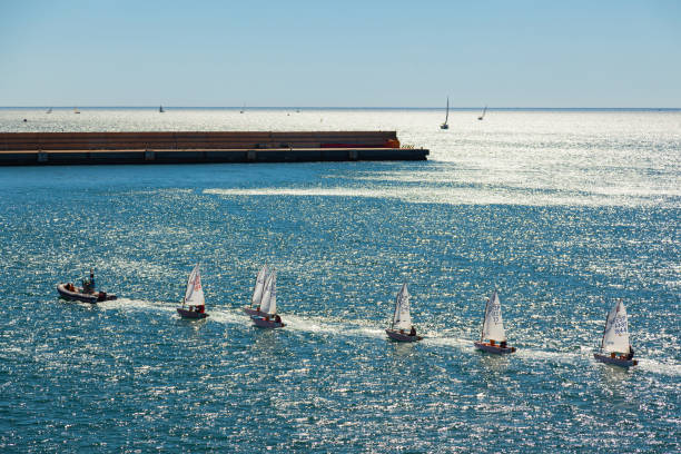 The coach's boat accompanies small children's sailboats in the sea bay. Yachting school. Motril, Granada, Spain - 10.01.2022: The coach's boat accompanies small children's sailboats in the sea bay. Yachting school. sailing dinghy stock pictures, royalty-free photos & images