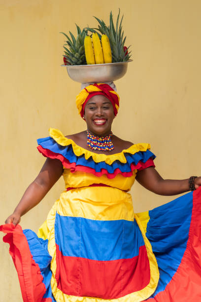 joyeuse vendeuse de rue de fruits frais de palenquera souriante dansant joyeusement dans la vieille ville de carthagène, colombie, femme afro-colombienne en costumes traditionnels - food caribbean street cartagena photos et images de collection