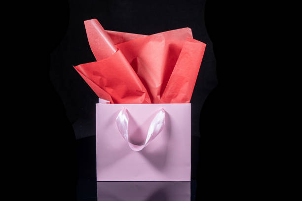 istock Craft paper gift bag with tissue paper isolated on a black background 1481436311