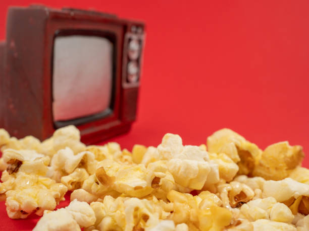 istock Popcorn and an old TV on a red background. Sweet popcorn on red. 1481437791
