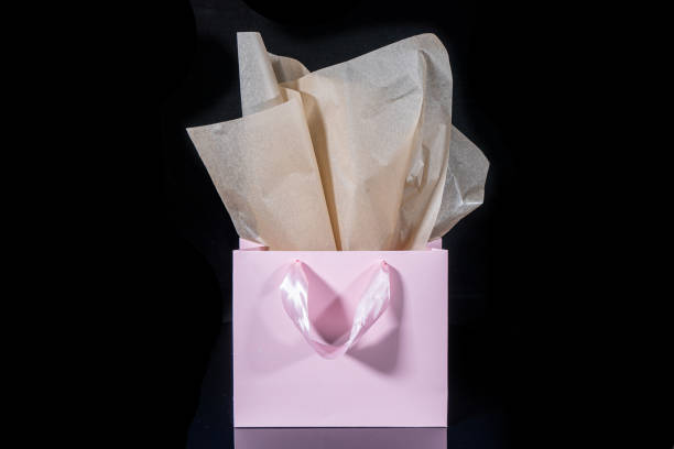 istock Craft paper gift bag with tissue paper isolated on a black background 1481438193