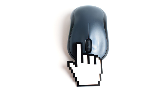 Hand-shaped cursor figurine clicks a computer mouse button. Creative helping hand concept.