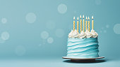 Blue birthday cake with yellow birthday candles on a blue background