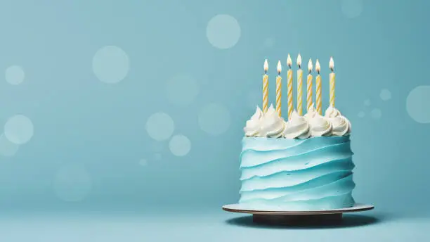 Photo of Blue birthday cake with yellow birthday candles on a blue background