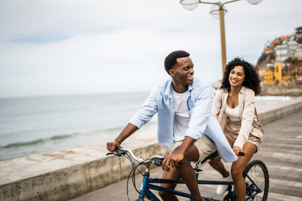 Young couple taking a ride on a double bicycle on coastline