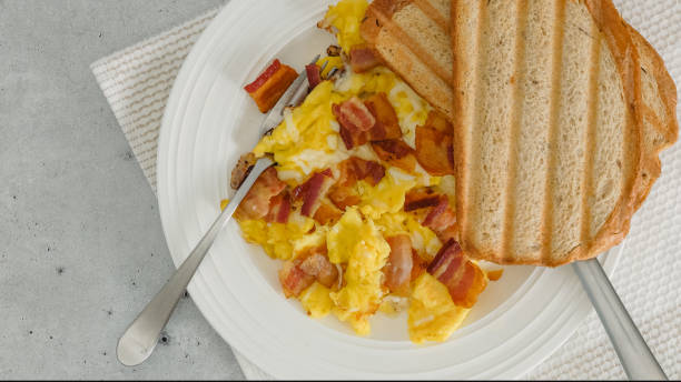 istock English breakfast. Scrambled eggs fried with bacon and cheese, and served with bread toast. Meal on a plate 1481444389