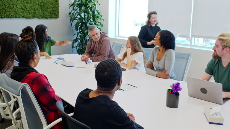 Diverse Group Of People Sitting In Board Room Talking To Each Other In Fulfillment Center Office