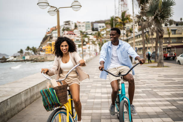 Young couple during a bike ride on the seacoast Young couple during a bike ride on the seacoast tourist couple candid travel stock pictures, royalty-free photos & images