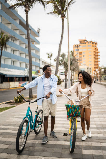 młoda para spacerująca z rowerami po wybrzeżu - candid people casual bicycle zdjęcia i obrazy z banku zdjęć