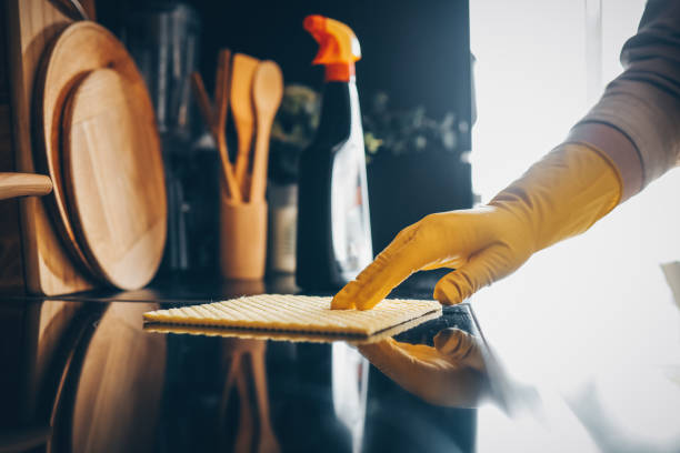 istock Closeup on woman's hands in yellow protective rubber gloves cleaning kitchen cabinets with sponge. 1481448175