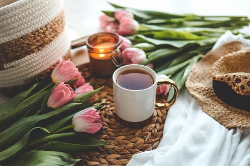 Beautiful spring composition, a cup of tea, tulips, a candle and a hat.