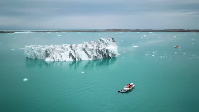 Aerial drone footage of an amphibian boat sailing among icebergs in Jokulsarlon