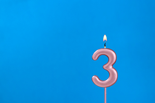 Number 3 - Burning anniversary candle on blue foamy background