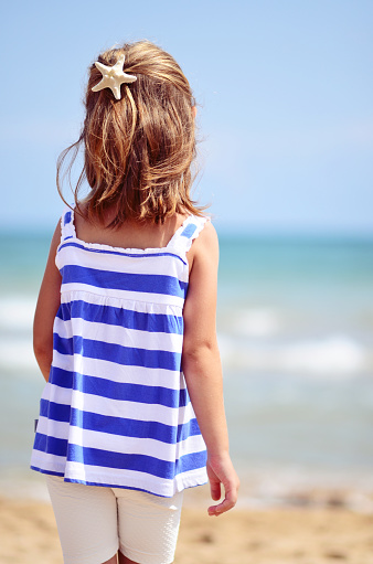 Little girl in back with starfish hairpin looking out to sea