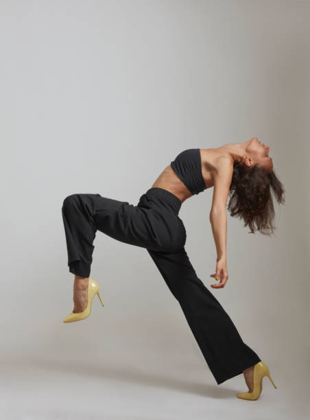 молодая женщина шагает, словно танцуя. - women healthy lifestyle fashion contemporary стоковые фото и изображения