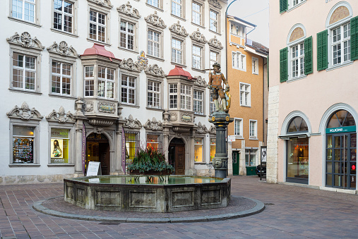 Old fountain with sculpture in Brilon city center with medieval space frame houses in the background