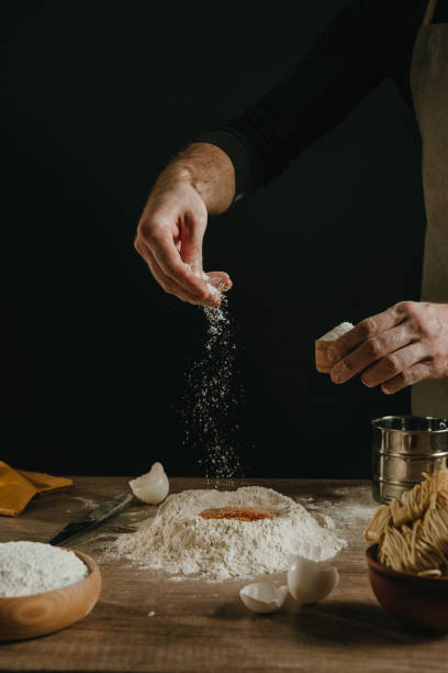 istock Unrecognizable man kneading dough on wooden background against dark wall 1481465946