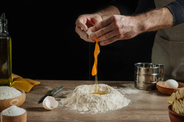istock Unrecognizable man kneading dough on wooden background against dark wall 1481466252