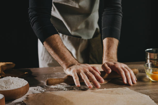 istock Unrecognizable man rolling out the dough with a rolling pin on wooden background 1481466305