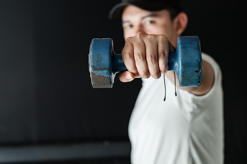 close-up of a Latino man's hand holding a blue dumbbell, working on muscular endurance.