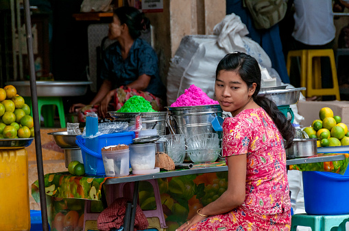 Mandalay, Myanmar - nov 3, 2012: a young woman sells juices and colorful drinks on a counter in the Mandalay market.