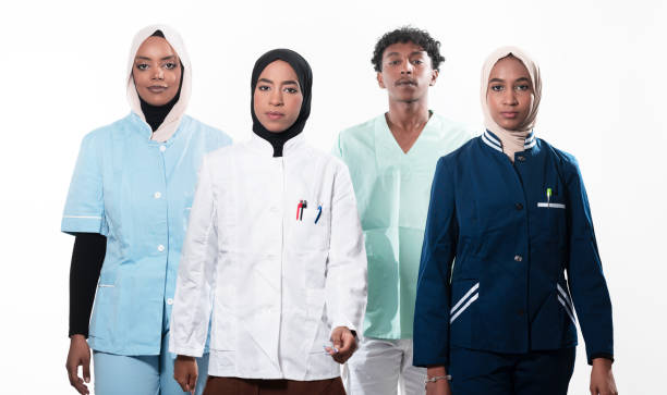 istock Closeup front view of group of mixed age doctors and nurses standing side by side and looking at the camera. Young Middle Eastern female in a team with African American male doctor. 1481475964