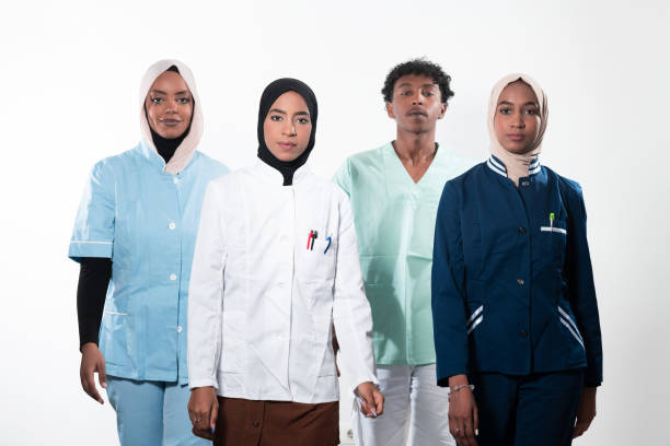 istock Closeup front view of group of mixed age doctors and nurses standing side by side and looking at the camera. Young Middle Eastern female in a team with African American male doctor. 1481476079