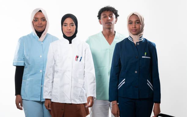 istock Closeup front view of group of mixed age doctors and nurses standing side by side and looking at the camera. Young Middle Eastern female in a team with African American male doctor. 1481477255