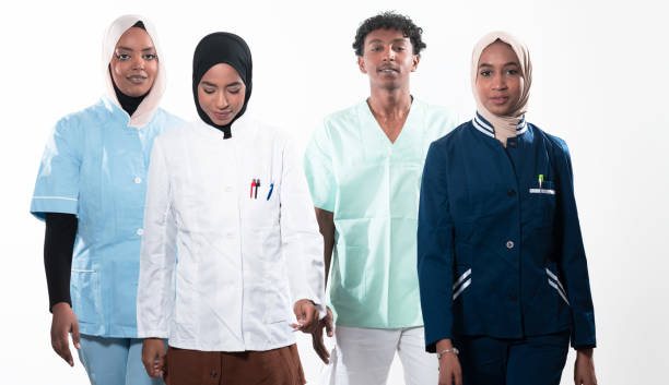 istock Closeup front view of group of mixed age doctors and nurses standing side by side and looking at the camera. Young Middle Eastern female in a team with African American male doctor. 1481477394