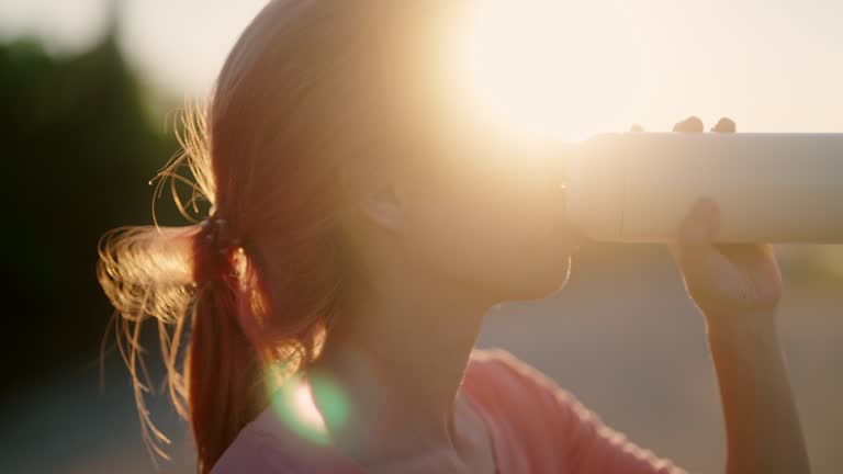 Woman sprinting and drinking water at sunset