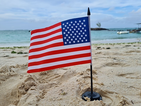 American flag on the beach and 4th of July Independence Day to commemorate or presidents. Stars and stripes patriotic symbol of USA