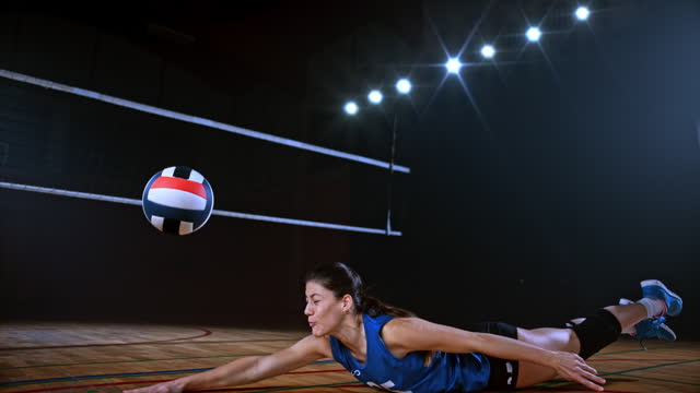 SLO MO LD Female volleyball player in blue jersey diving and saving the ball