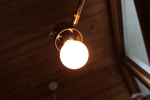 a lightbulb shines eagerly on a golden fixture.