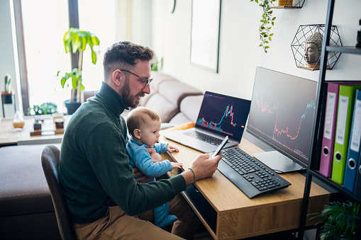 Man looking at currency trading app on his smart phone from his home office.