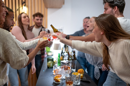 Two generations have a party at home with their partners, friends celebrate, sing, dance to music, sing karaoke on a mobile phone, have fun, drink alcoholic and non-alcoholic drinks A multi-racial society.