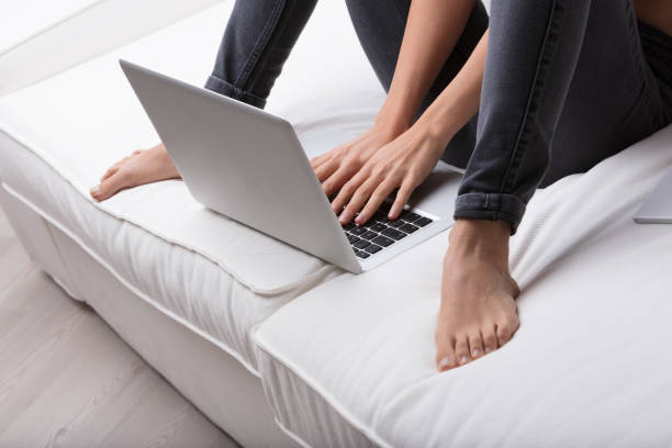 A young female student sitting on the floor, using laptop for studying. Drinking tea.