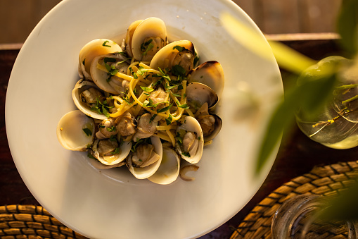 Tasty pasta meal with clams on dinning table at the restaurant outdoors, ready to eat.