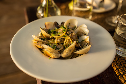 Tasty pasta meal with clams on dinning table at the restaurant outdoors, ready to eat.