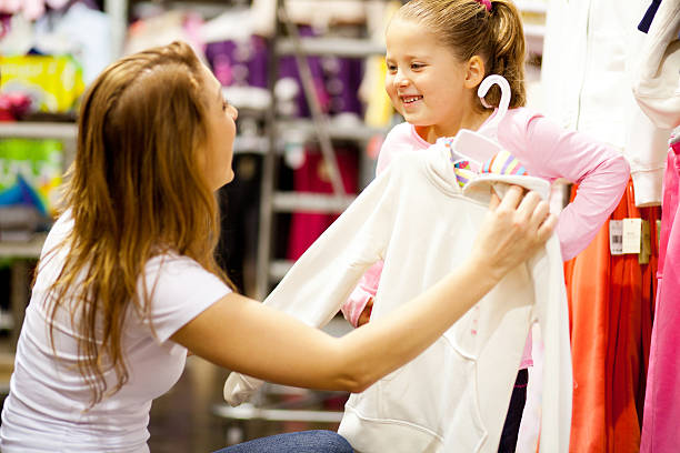 mother and daughter shopping for clothes happy mother and daughter shopping for clothes clothing store stock pictures, royalty-free photos & images