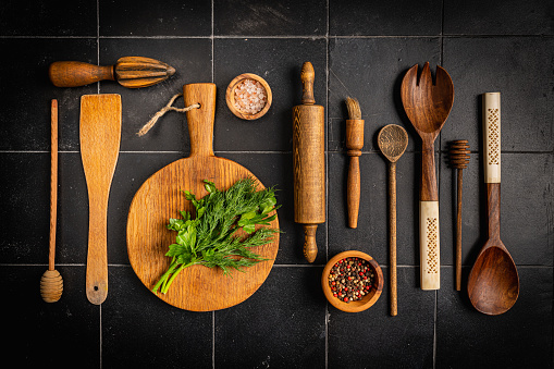 Old wooden kitchen utensils or cooking tools on black background, top view, flat lay. Kitchenware collection with copy space. Cooking background.