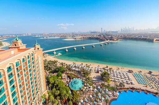Balcony view of the grounds and swimming pool of the Atlantis Palm resort at the Palm Jumeirah island complex along the coast of Dubai, United Arab Emirates. In the distance is the city of Dubai connected by the Palm Monorail.