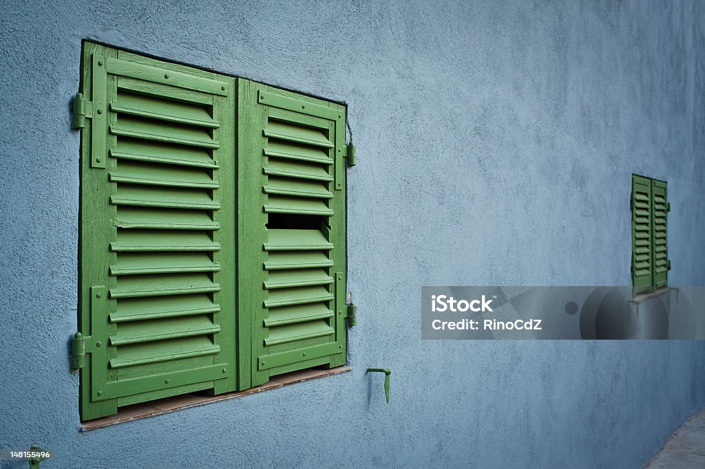 Blue Wall With Green Windows, Perspective House facade with blue wall and two green windows. Selective focus on left window. Perspective view. Blue Stock Photo