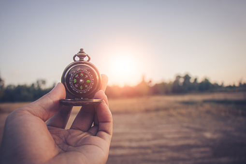 Compass of tourists on mountain at sunset sky.