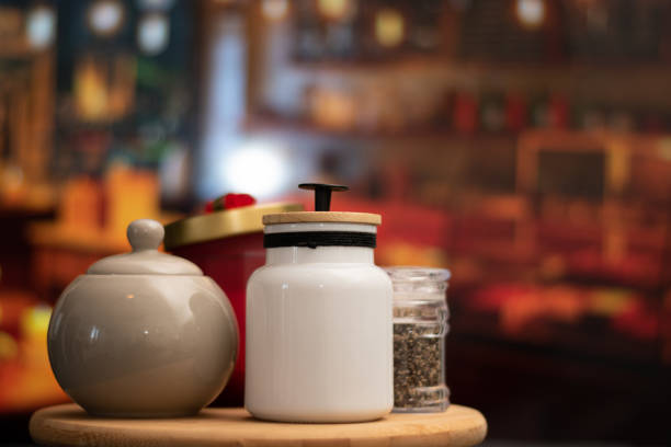 Mugs of sugar and salt containers style vintage over a table in night restaurant with selective focus and bokeh background Mugs of sugar and containers style vintage salt pepper ingredient black peppercorn stock pictures, royalty-free photos & images